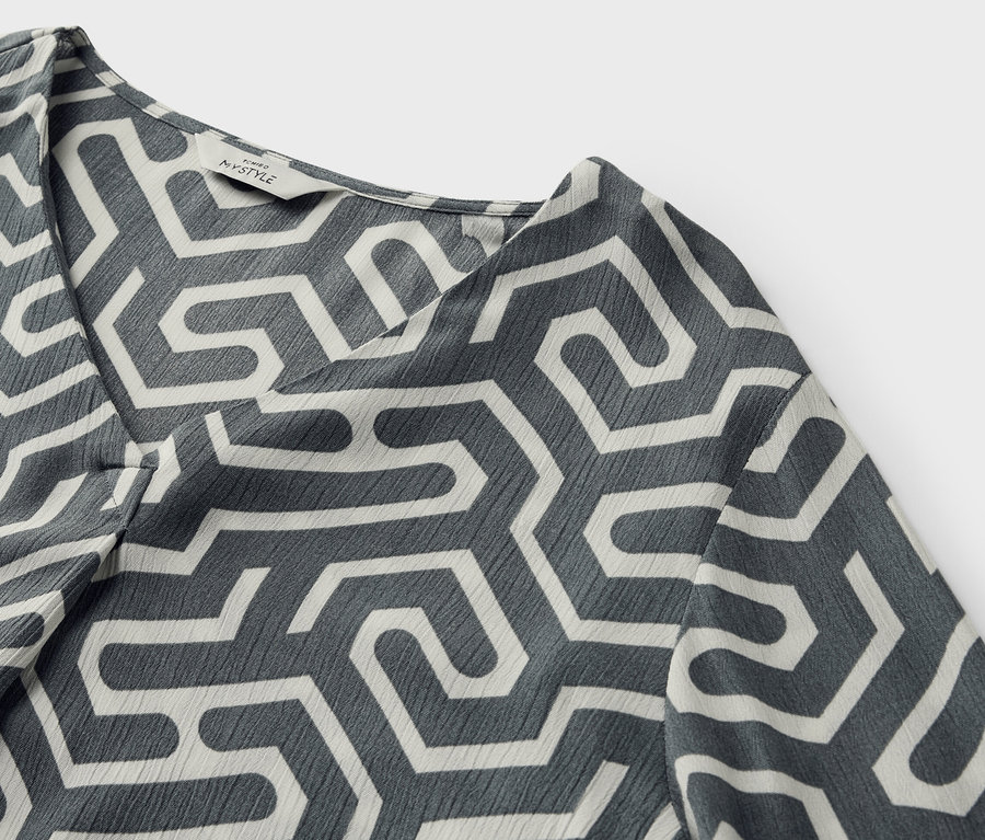 Detailansicht einer Bluse in Crinkle-Optik mit geometrischem Muster.