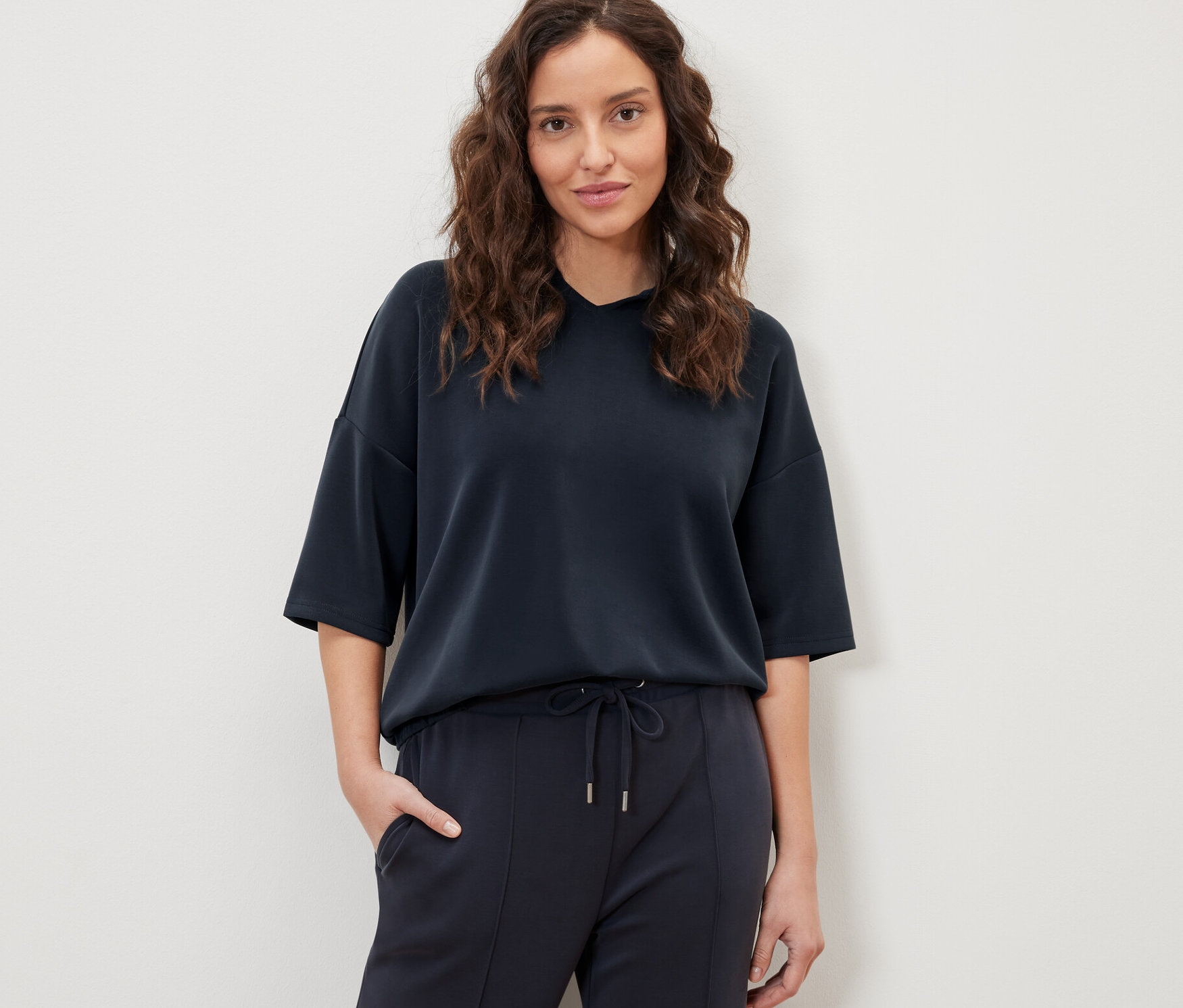 Frau posiert in dunkelblauem Hoodie aus Modal-Mix und Hose.