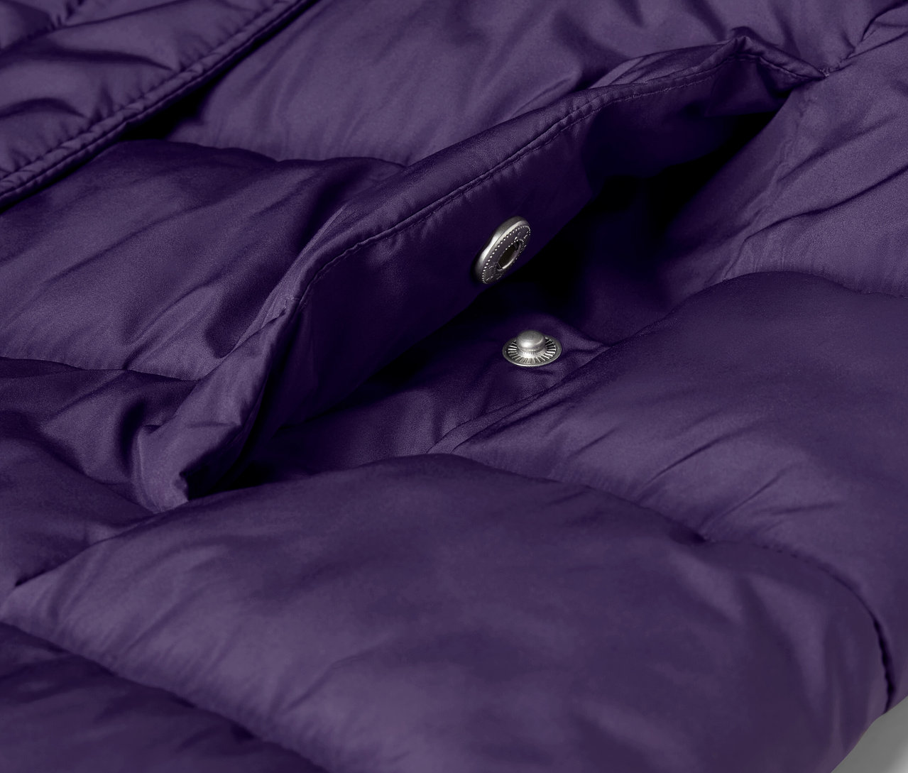 Detailaufnahme einer lila Steppjacke mit Tasche und silbernen Druckknöpfen.