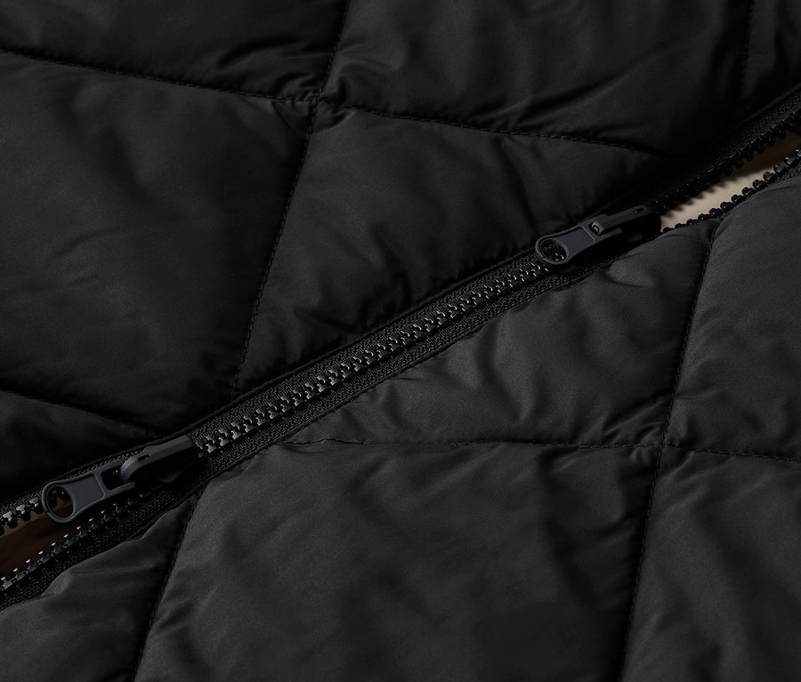Detailaufnahme einer schwarzen Steppjacke mit Reißverschluss.