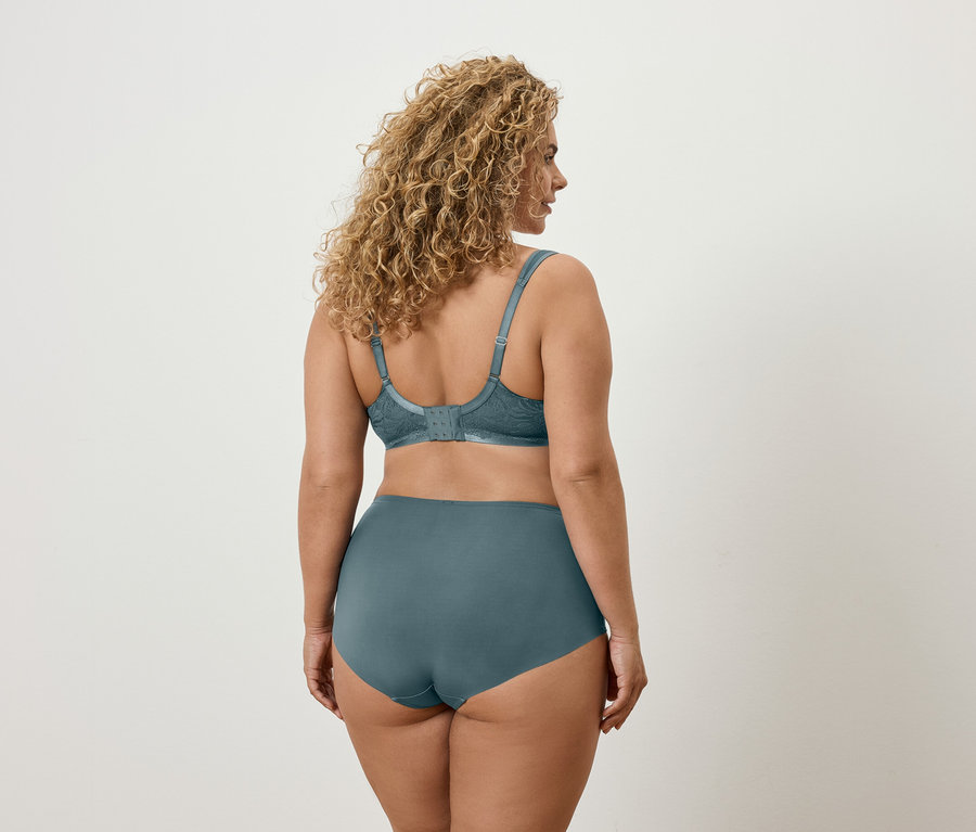 Rückansicht einer Frau mit welligem Haar, die einen blaugrünen BH und Slip trägt.