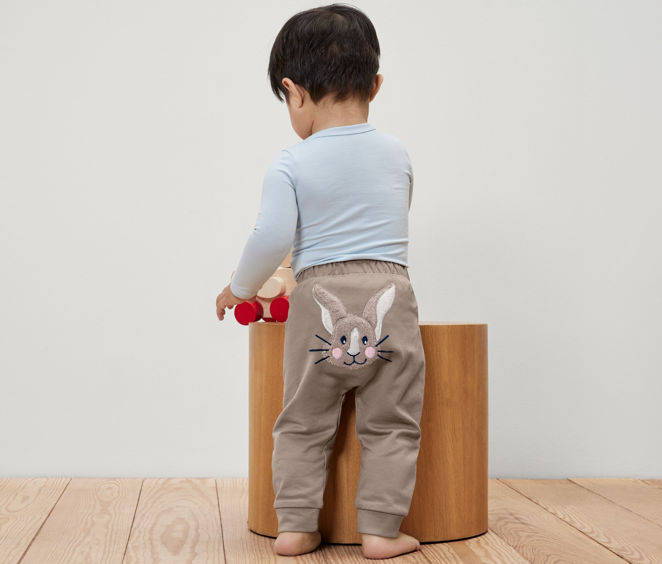 Ein Kleinkind steht mit dem Rücken zur Kamera und trägt eine Babyhose mit einem Hasenbild.