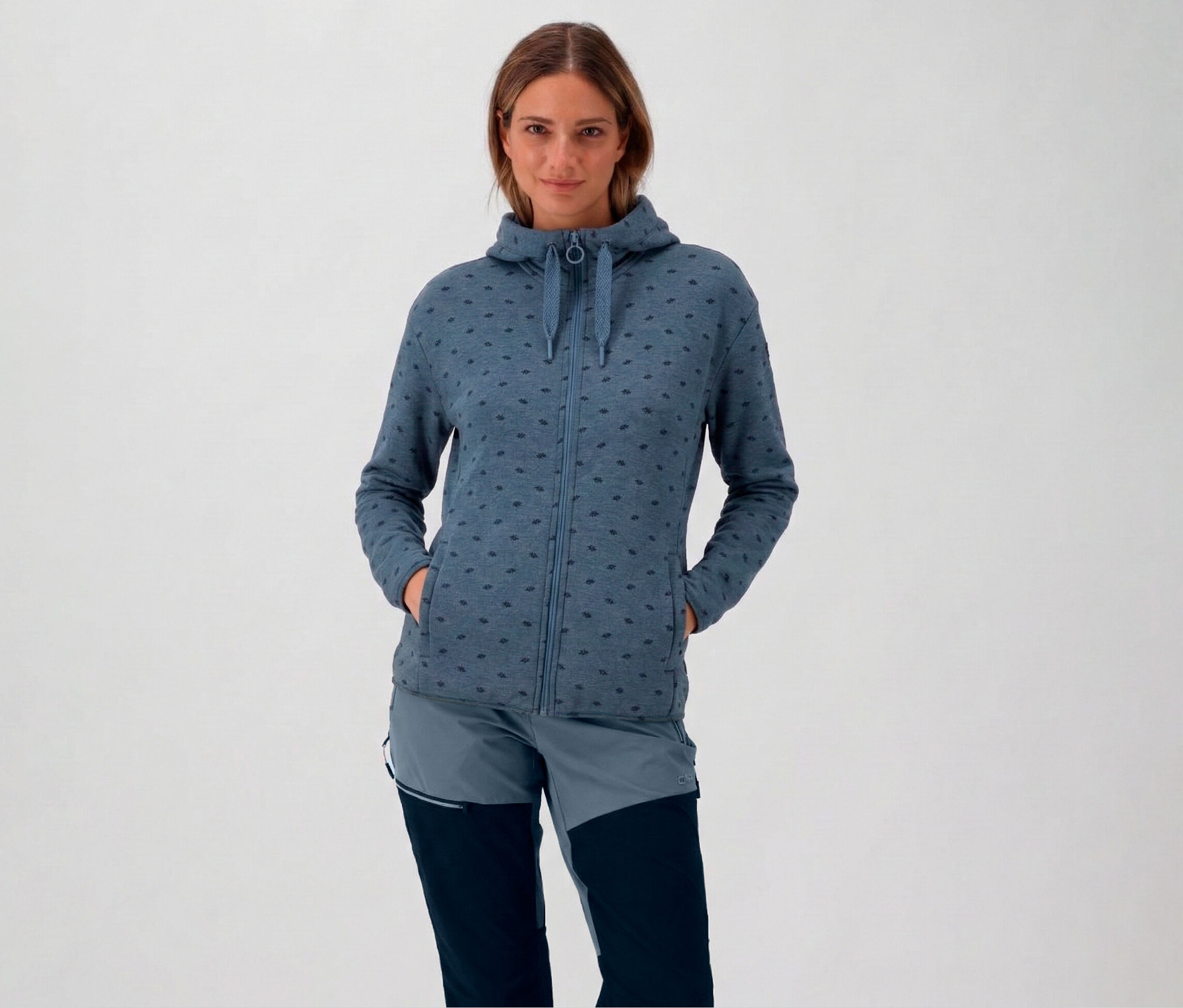 Frau mit Kapuze und blauer CMP Damen-Fleece-Jacke mit Kapuze und Händen in den Taschen.