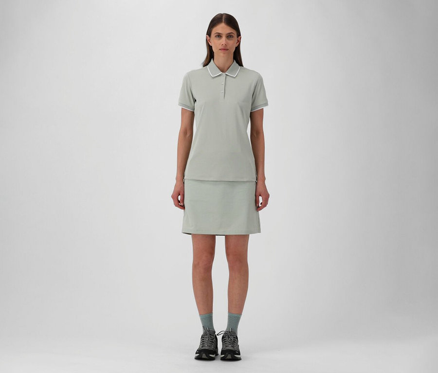 Frau in CMP Damen-Outdoor-Rock und pistazienfarbenem CMP Damen-Poloshirt aus Stretch-Piqué, dazu graue Socken und Wanderschuhe.