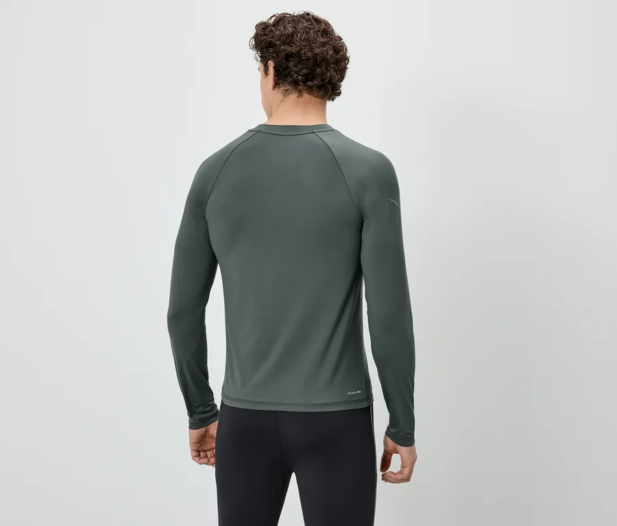 Rückansicht eines Mannes mit lockigem Haar, der ein graues, langärmeliges Shirt und schwarze Leggings trägt.