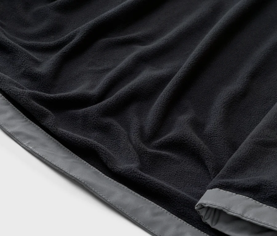 Nahaufnahme von marineblauem Fleece-Stoff mit grauer Bordüre, der sich in Falten legt.