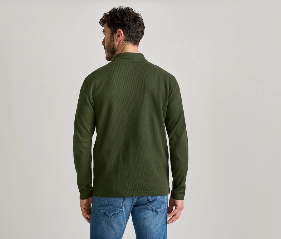 Rückansicht eines Mannes mit Bart, der ein olivgrünes Cordhemd und Jeans trägt.