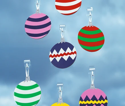 Sieben verschiedenfarbige, kreisförmige Weihnachtskugelornamente hängen an transparenten Clips vor einem blauen Hintergrund.