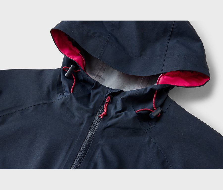 Dunkelblaue Jacke mit Kapuze, pinkem Innenfutter, roten Kordelzügen mit schwarzen Stoppern und Reißverschluss.