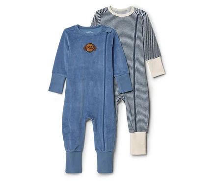 Zwei Baby-Strampler liegen nebeneinander. Einer ist blau und samtig mit einem Löwenkopf-Patch, der andere ist blau-weiß gestreift mit cremefarbenen Bündchen.