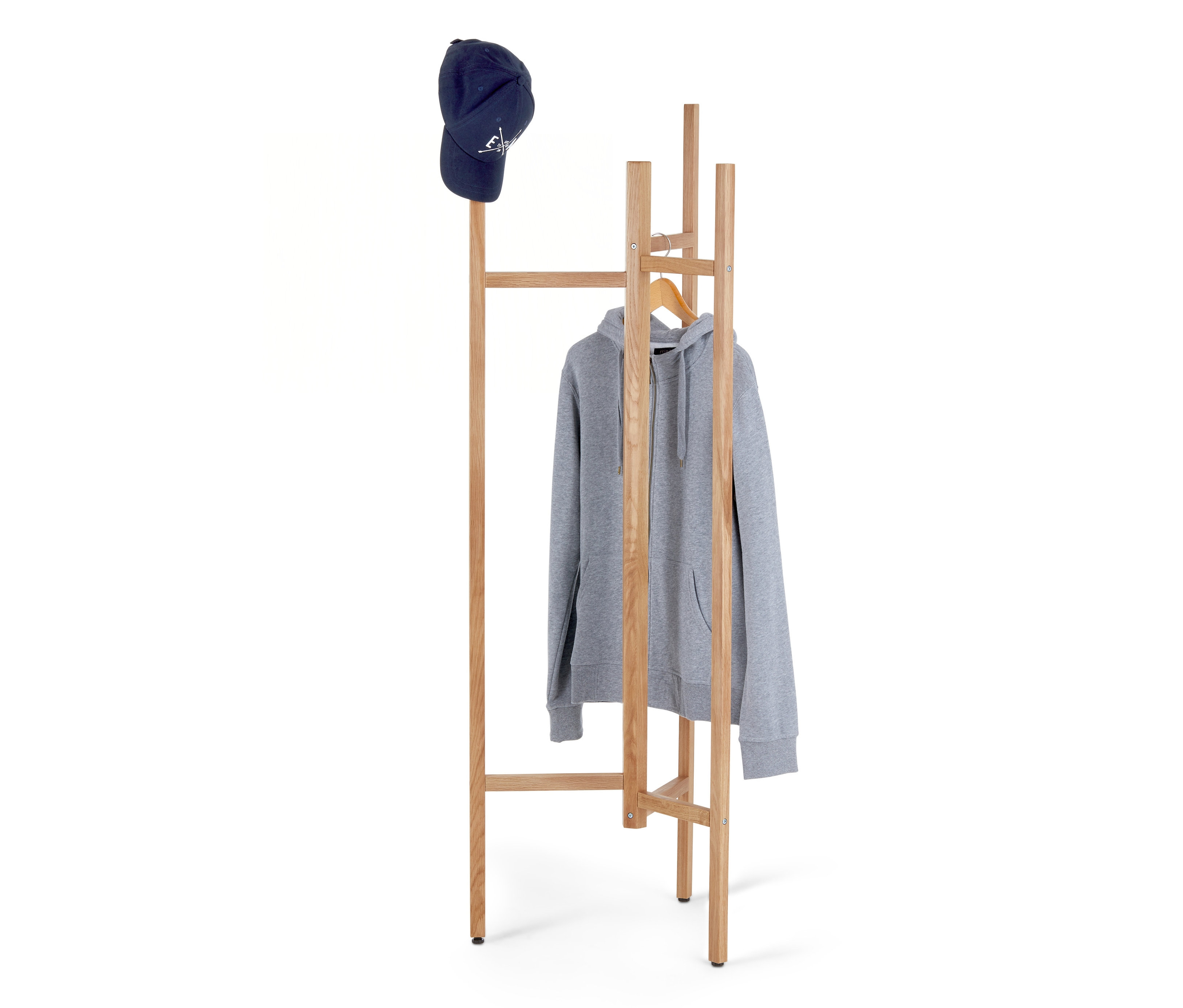 Eine blaue Baseballkappe liegt auf einem hölzernen Garderobenständer, an dem ein grauer Kapuzenpullover mit Reißverschluss hängt.