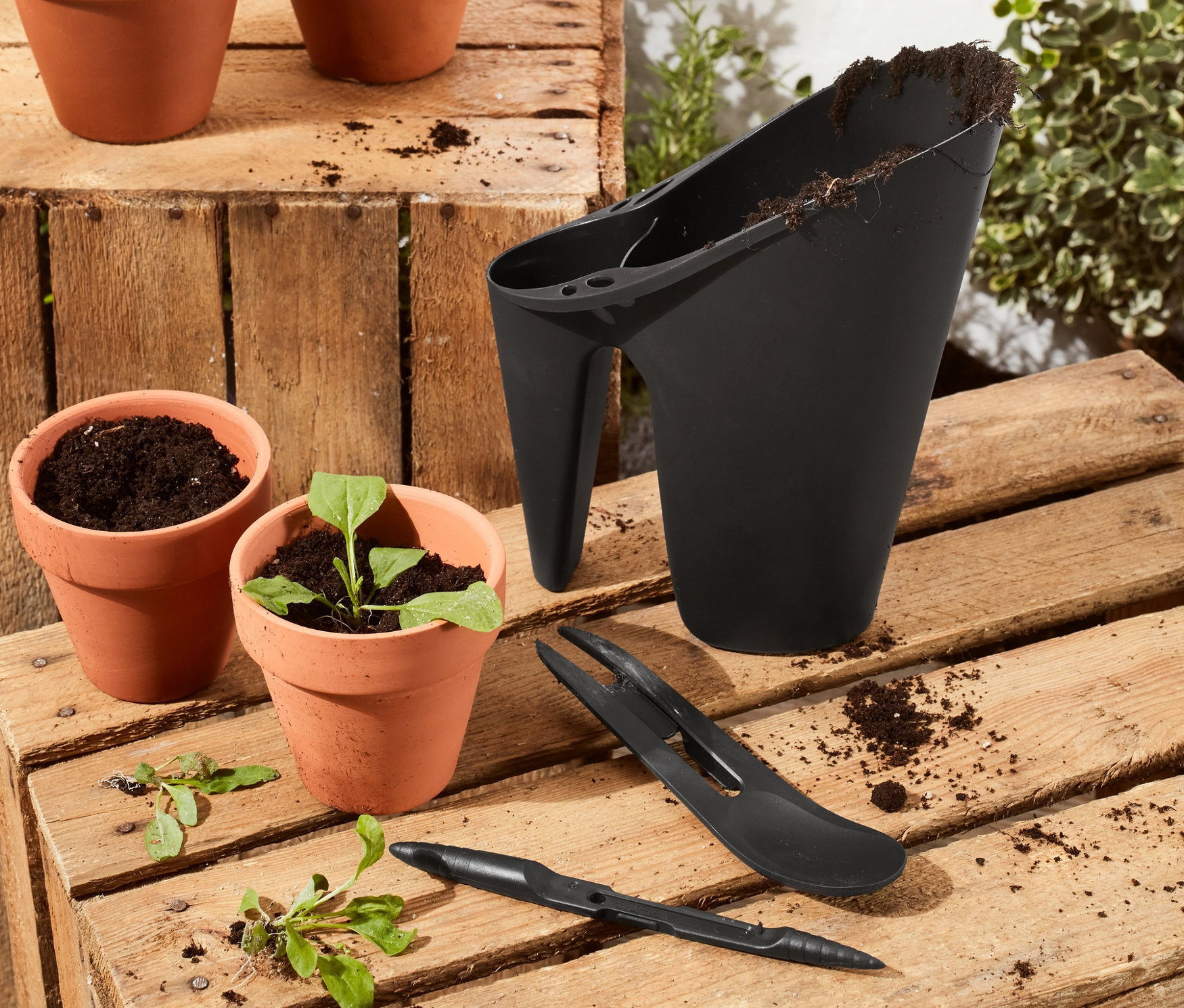 Gärtner-Set und Blumentöpfe auf einer Holzkiste.