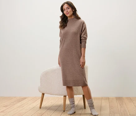Frau posiert in einem Cashmere-Strickkleid neben einem Teleskop-Schuhanzieher.