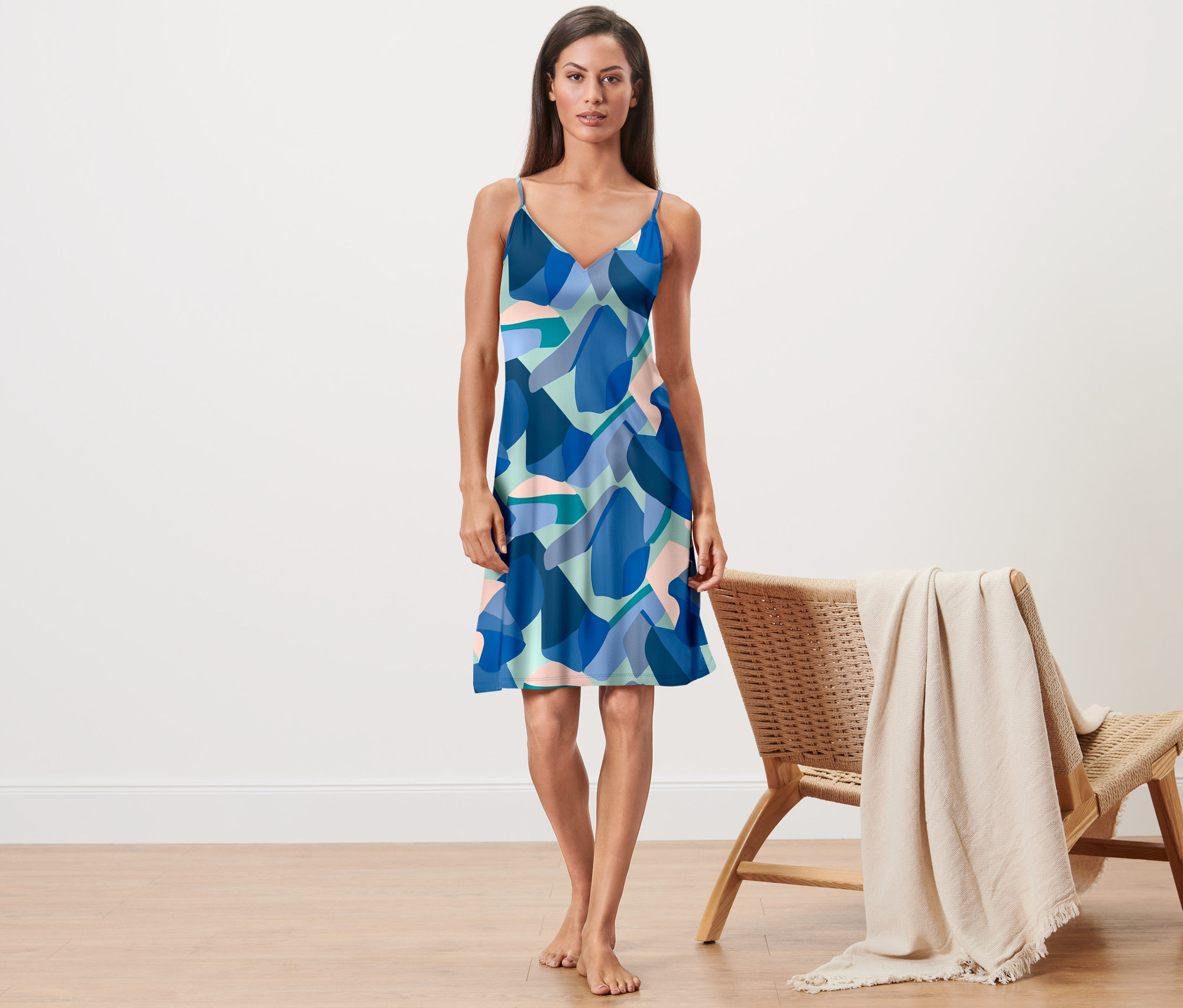 Frau steht barfuß da und trägt ein Trägernachthemd mit blauem Muster.