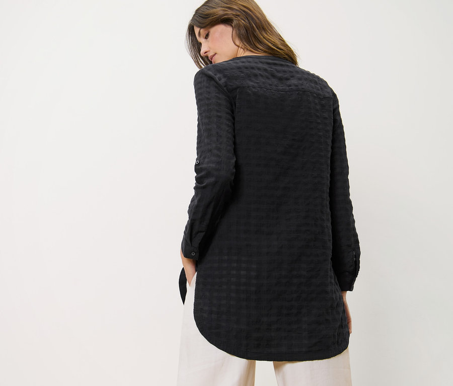 Frau trägt Longtunika mit Webstruktur und Hose.