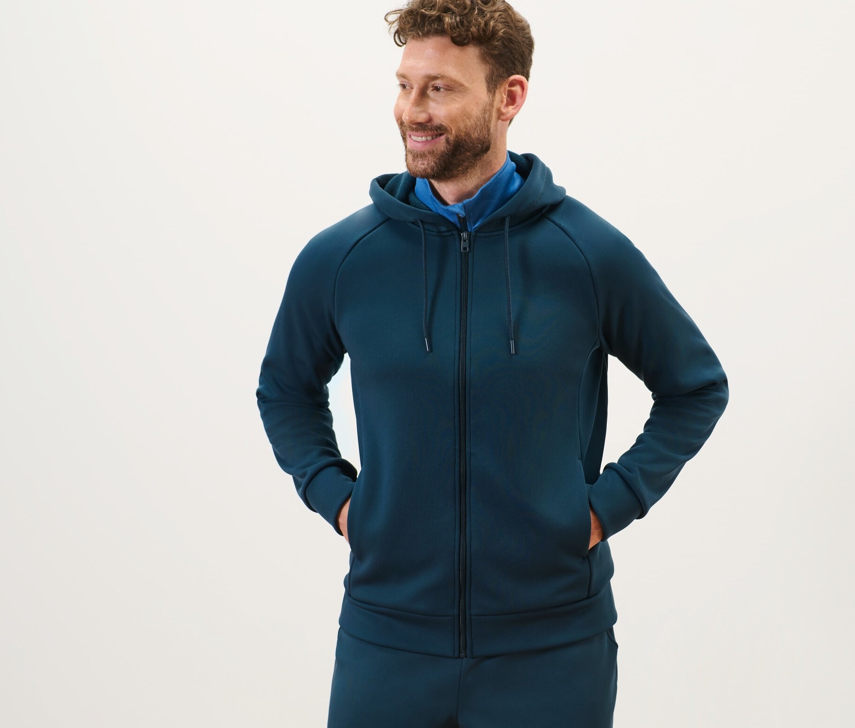 Mann mit Bart steht und trägt eine Funktions-Kapuzenjacke.