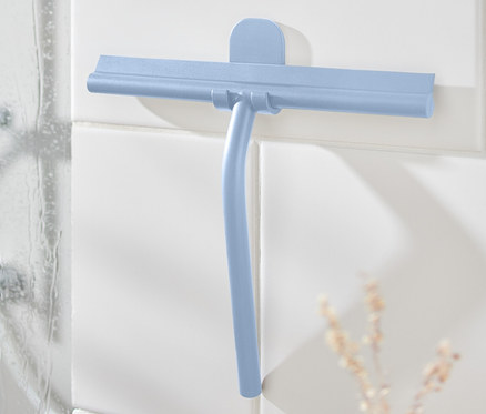 Blauer Badwischer mit Wandhalterung an weißen Fliesen neben der Dusche.