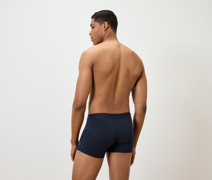 Mann mit freiem Oberkörper trägt dunkelblaue Boxershorts.