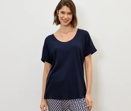 Frau trägt ein marineblaues Shirt aus Leinenmix und gemusterte Hosen.
