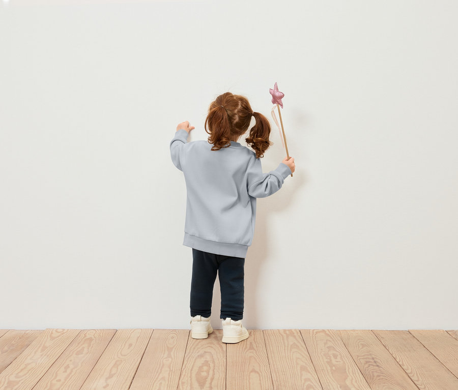 Mädchen mit blauem Pullover hält einen Zauberstab mit einem Stern.