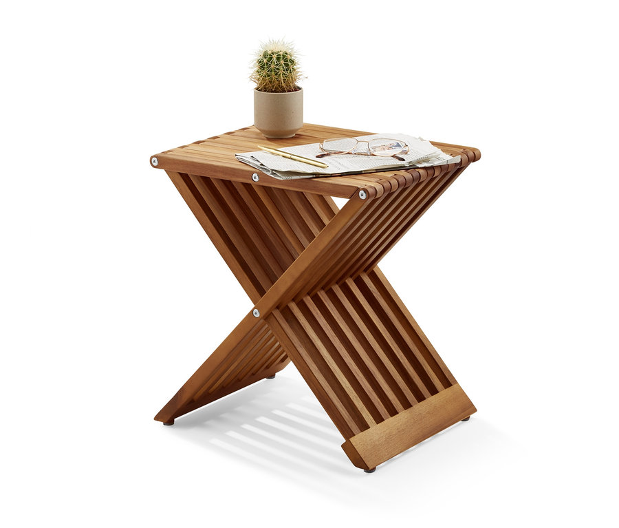 Auf einem Klapphocker liegen ein Kaktus im Topf, eine Brille, ein Stift und ein Stück Papier.