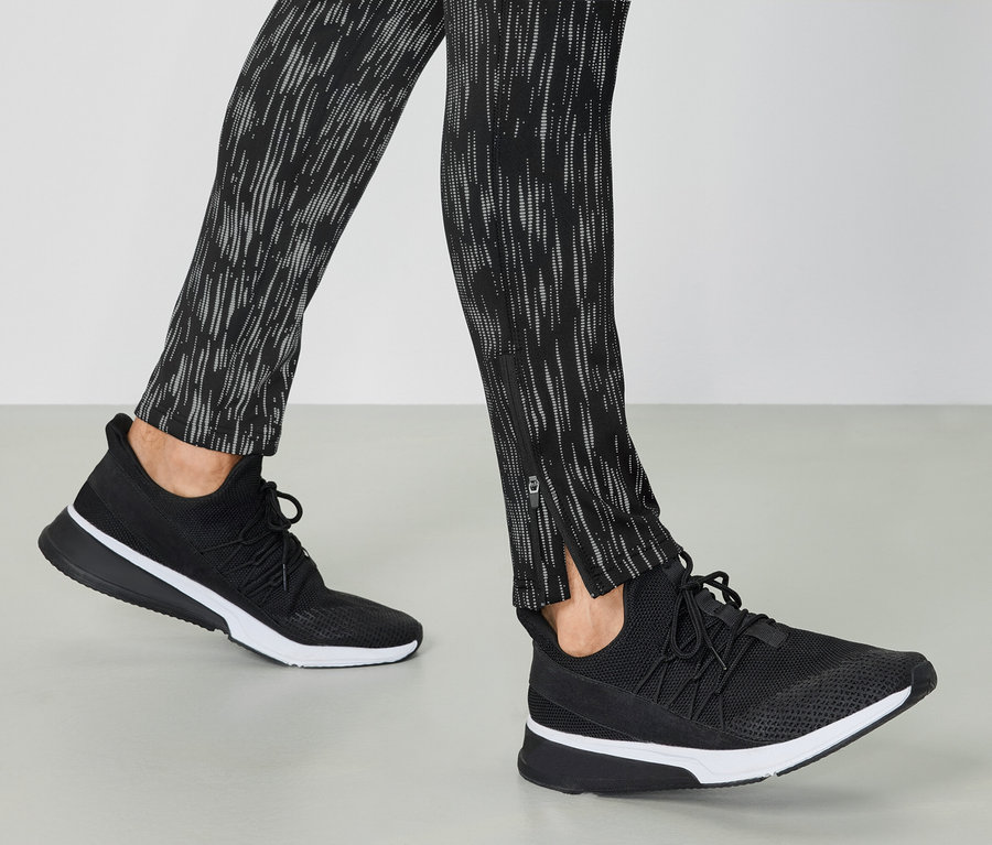 Beine in schwarzen Sportschuhen und gemusterten Leggings.