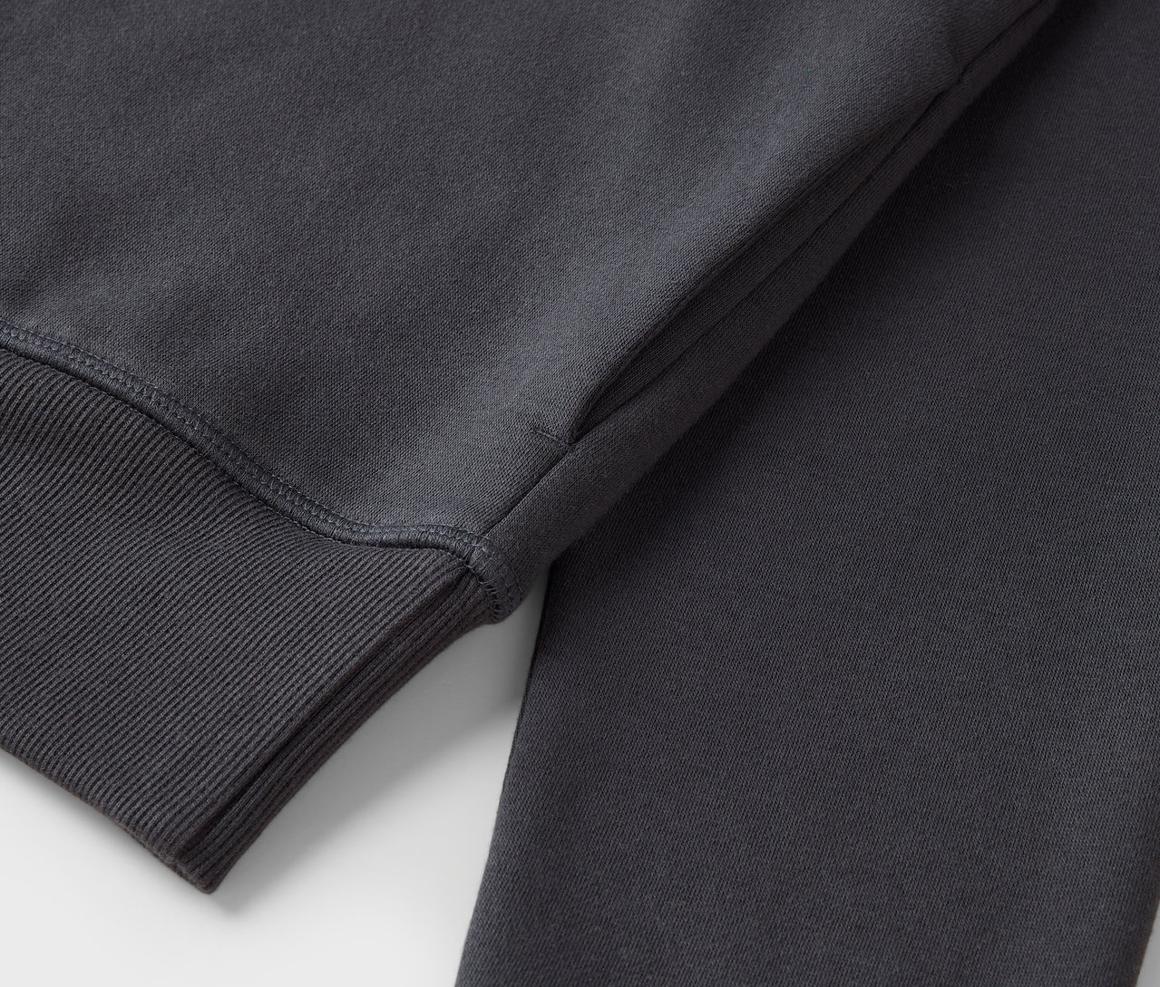 Detailaufnahme eines grauen Sweatshirts mit geripptem Ärmelbündchen.