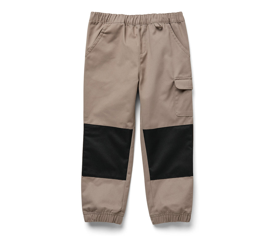 Eine beige Kinder-Outdoorhose mit schwarzen Flicken an den Knien.