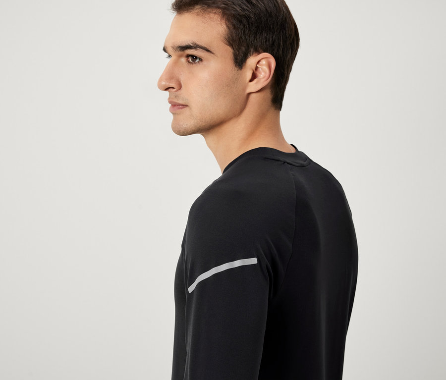 Mann im Profil, trägt ein schwarzes Langarmshirt mit Reflektorstreifen.