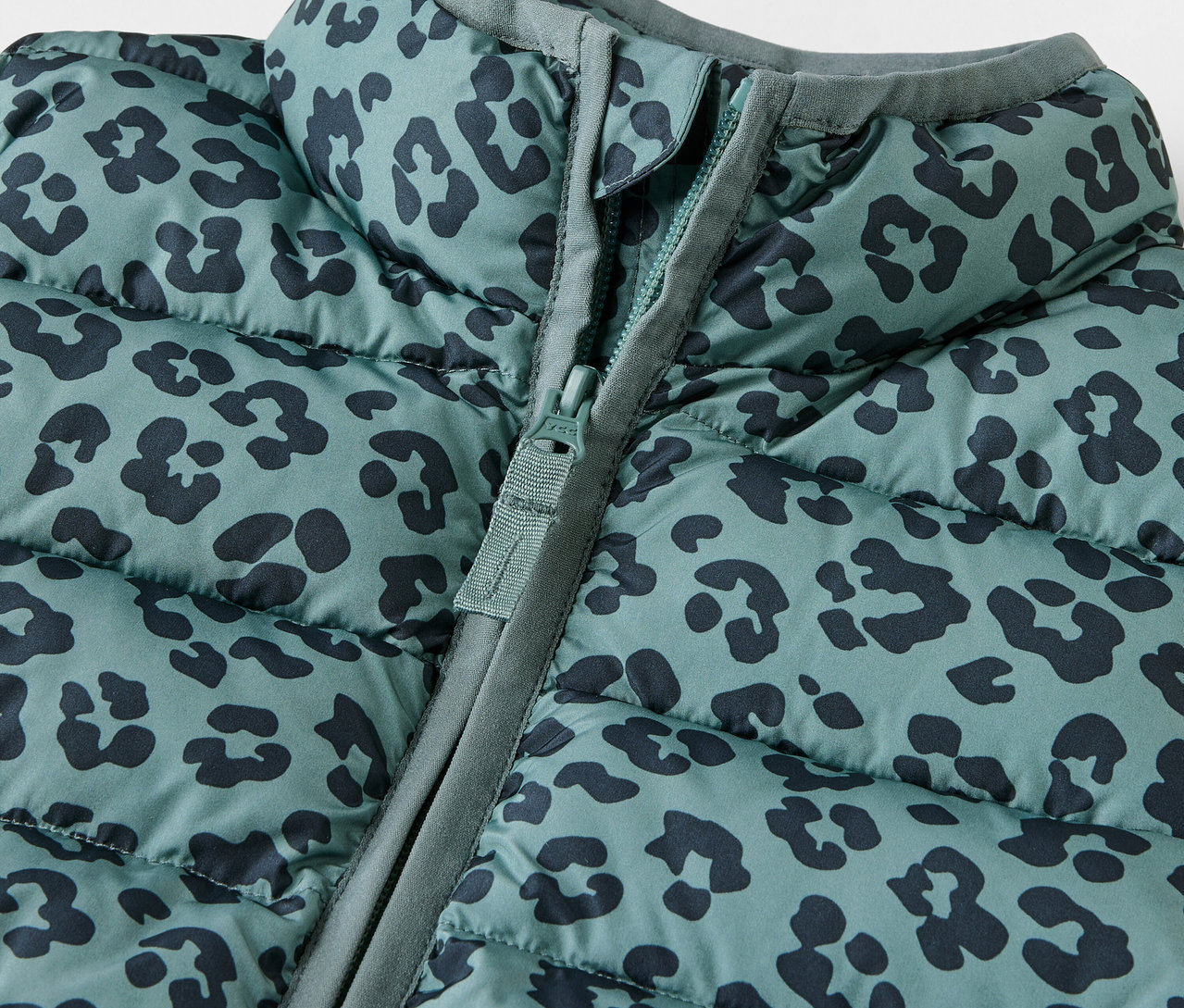 Detailaufnahme einer Kinder-Steppweste mit Tiermuster und Reißverschluss.