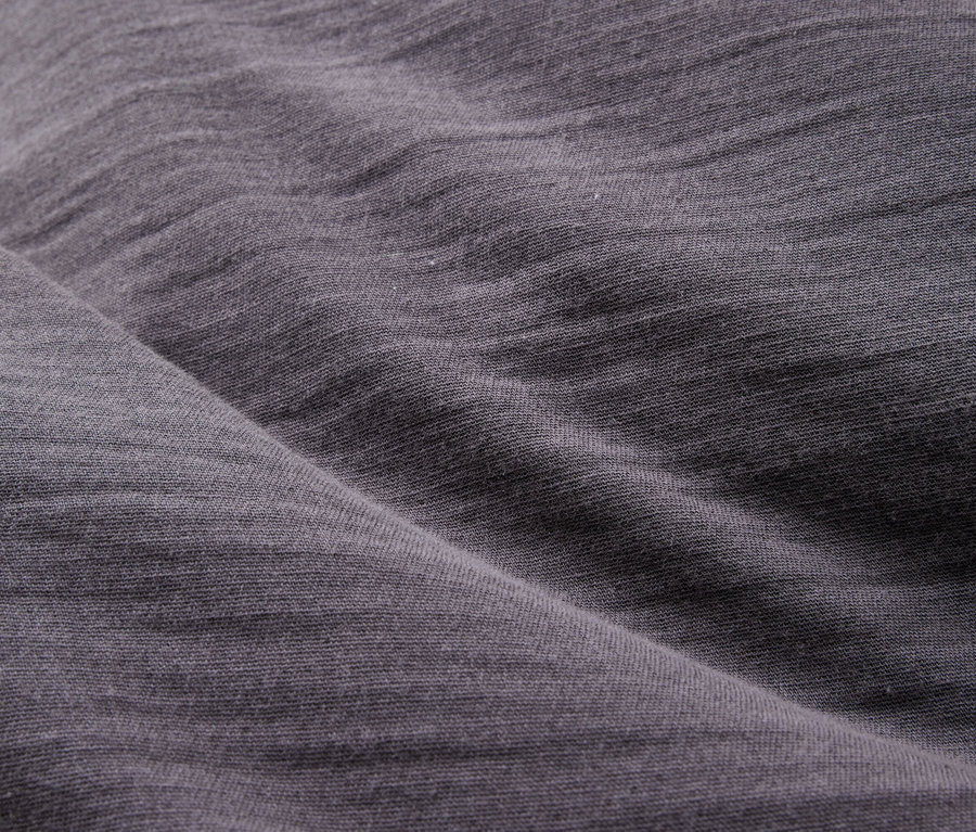 Nahaufnahme von drapiertem, grauem Stoff mit sichtbarer Textur und Faltenwurf.