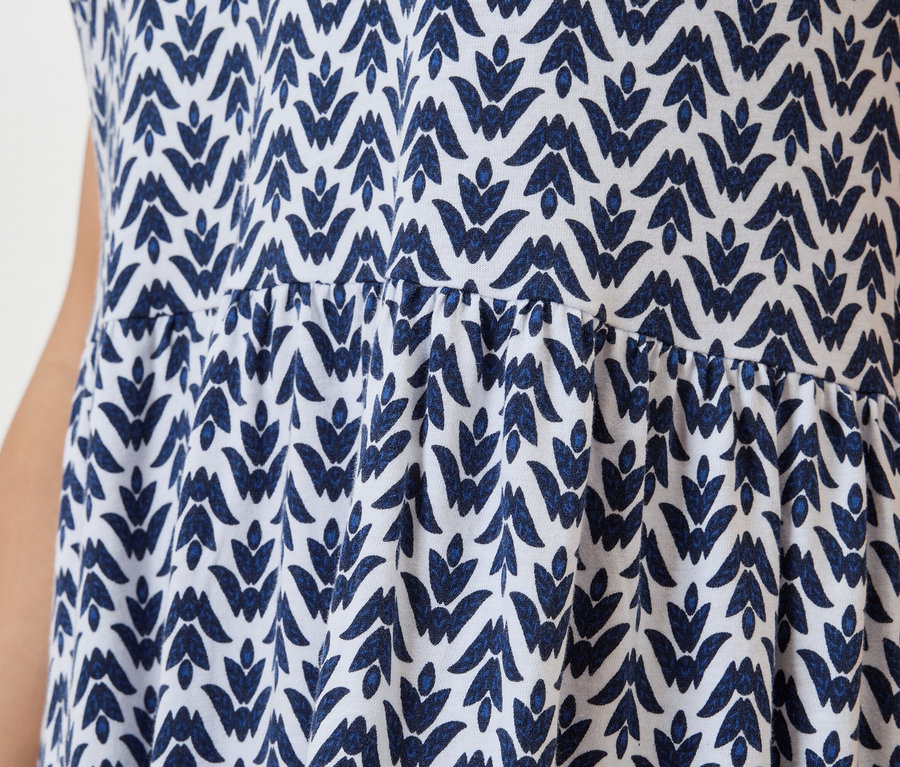 Nahaufnahme eines weißen Kleides mit blauem Blattmuster.