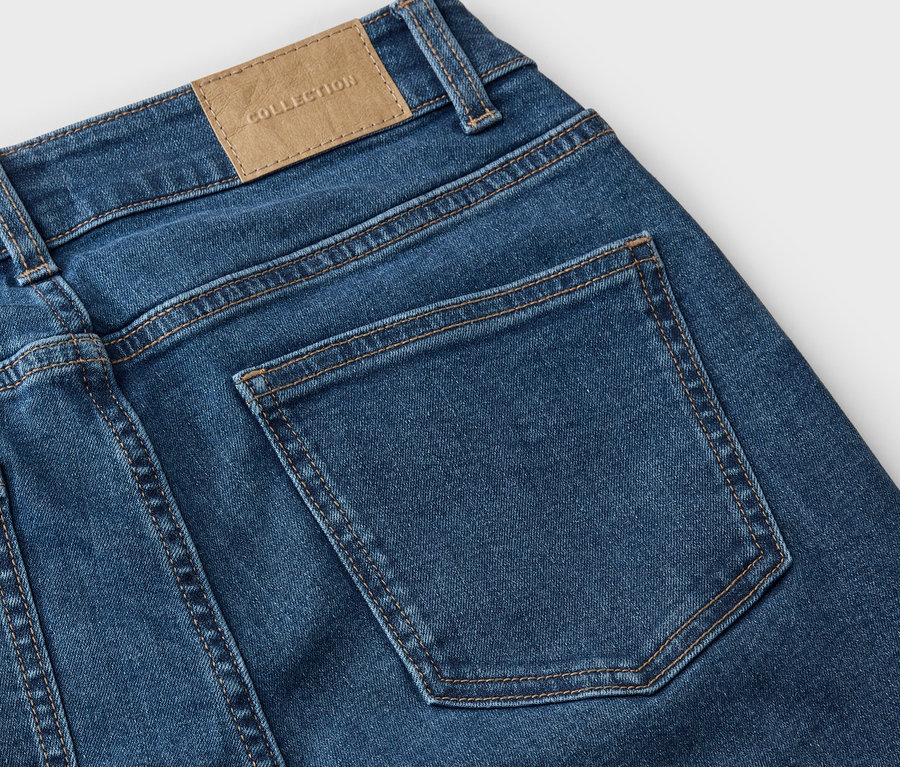 Detailansicht der Rückseite einer blauen Jeans mit einer Gesäßtasche und einem Lederetikett mit der Aufschrift "COLLECTION".