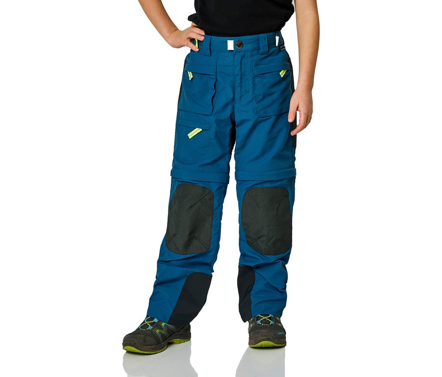 Kind trägt blaue Outdoor-Hose mit Kniepatches und Wanderschuhe.