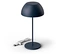 Eine dunkelblaue Lampe steht auf einem weißen Untergrund. Das Kabel der Lampe liegt daneben.