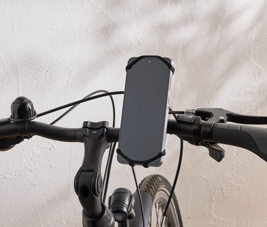 Nahaufnahme des Lenkers eines Fahrrads mit einem Smartphone, das mit einem Gummiband befestigt ist.