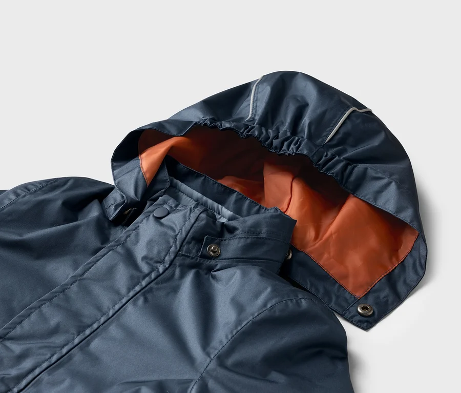 Nahaufnahme einer dunkelblauen Regenjacke mit orangefarbener Kapuze vor einem weißen Hintergrund.