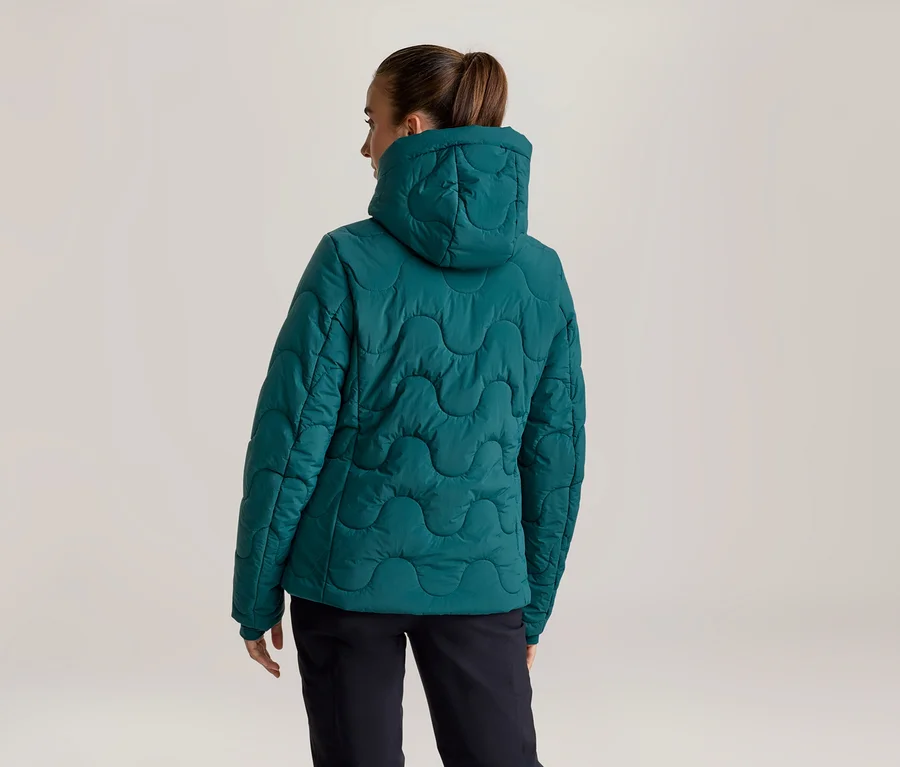Person von hinten in einer türkisen Steppjacke mit Kapuze und wellenförmiger Naht, dazu dunkle Hose.