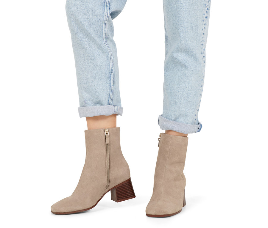 Beine in Jeans und Stiefeletten aus Veloursleder.