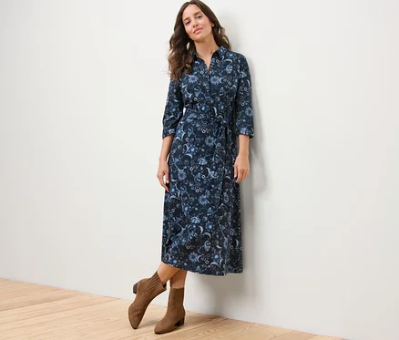 Frau posiert in einem bedruckten Jerseykleid und braunen Stiefeln.