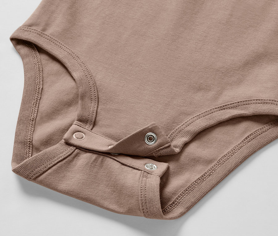Detailaufnahme eines braunen Baby-Bodys aus einem Baby-Set mit Druckknopfverschluss.
