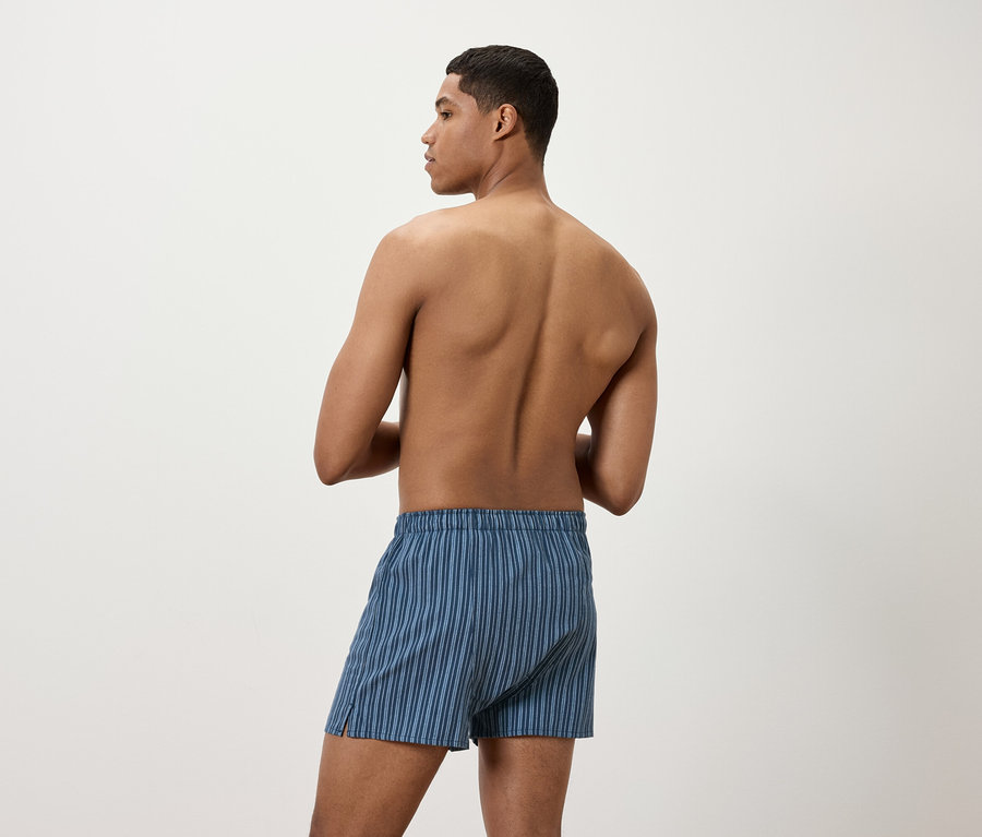 Mann von hinten trägt blaue gestreifte Boxershorts.