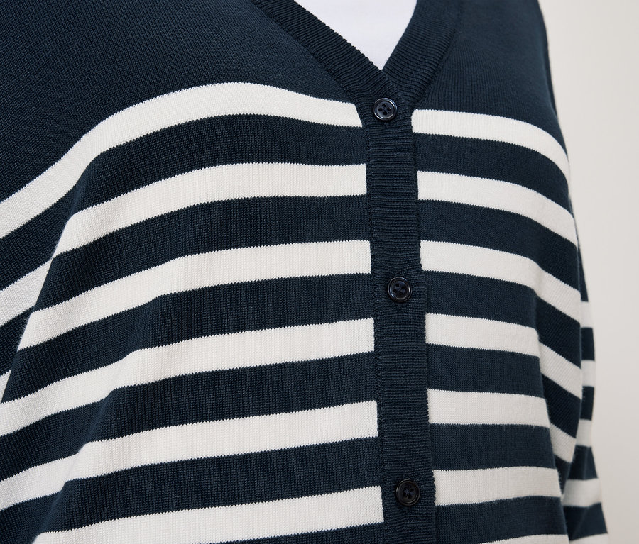 Detailansicht einer blauen Strickjacke mit weißen Streifen und Knöpfen.