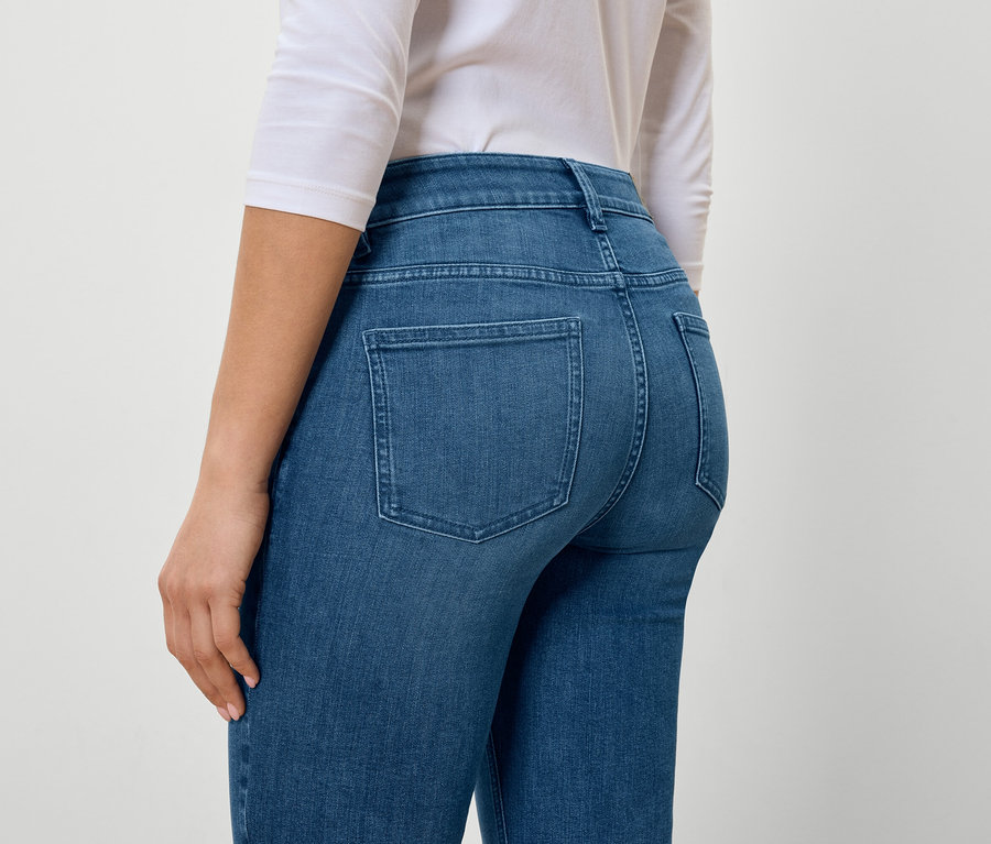 Rückansicht einer Frau in blauen Jeans und weißem T-Shirt.