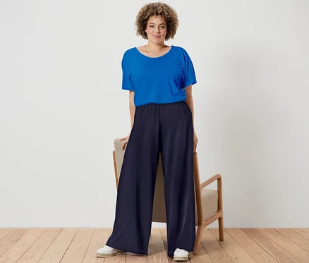 Frau posiert in kobaltblauem Shirt aus Leinenmix und dunkelblauer Palazzohose.