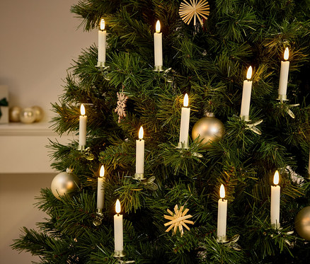Detailaufnahme eines Weihnachtsbaums mit Dekorationen und kerzenförmigen Lichtern.