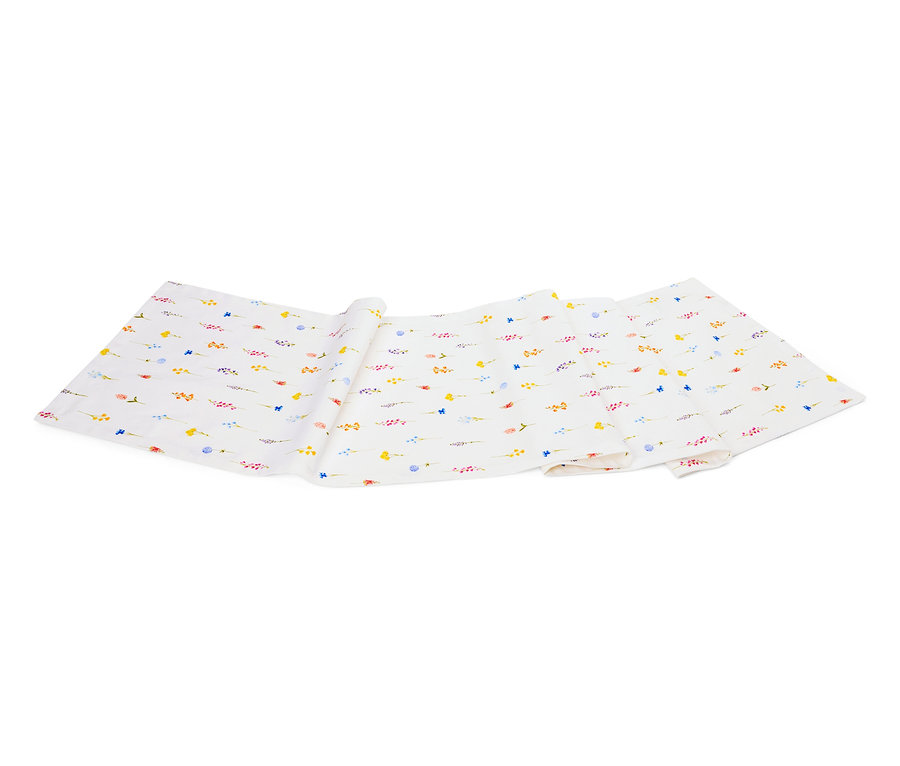 Ein weißes Tuch mit einem Muster aus kleinen bunten Blumen liegt gefaltet auf einem weißen Untergrund.