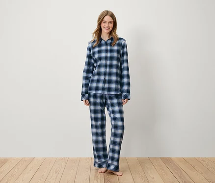 Eine Frau steht und trägt einen blau karierten Pyjama.