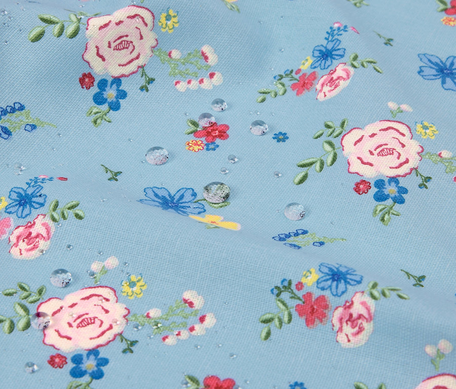 Nahaufnahme eines hellblauen Stoffes mit Blumenmuster und Wassertropfen.