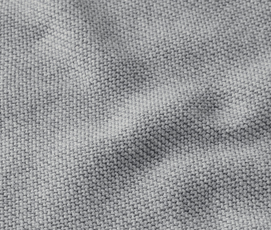 Nahaufnahme eines grauen Strickstoffes mit leichter Faltenbildung.